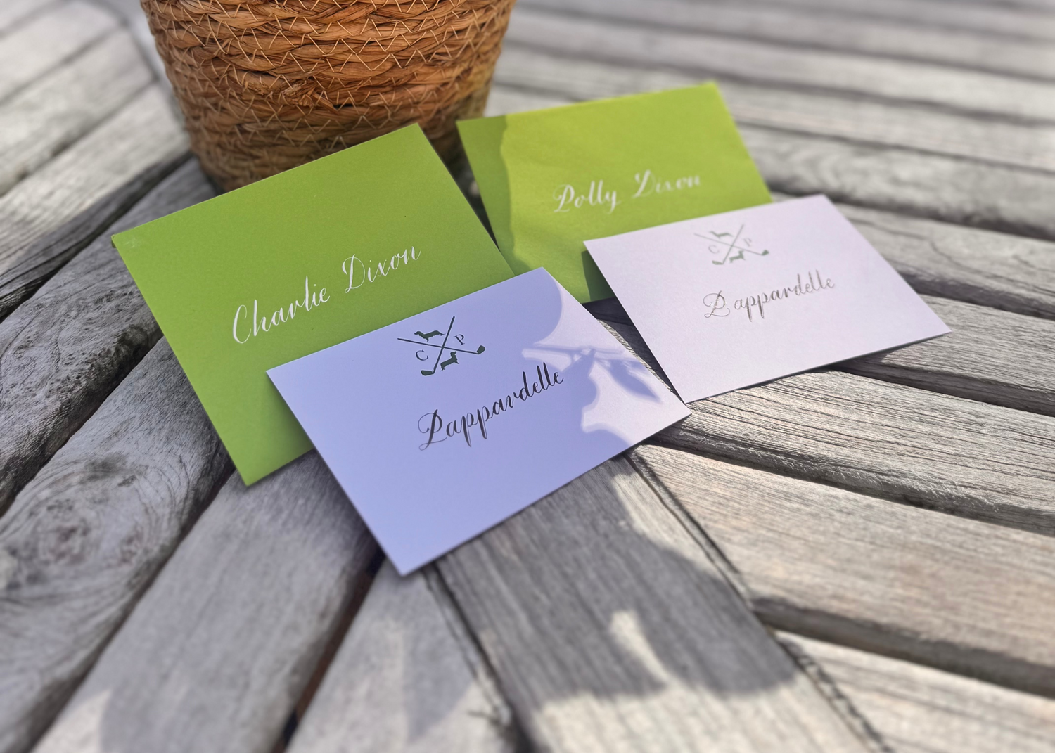 Four name cards on a wooden surface with a potted plant in the background
